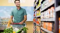 Portrait of smiling man walking in aisle with his trolely at supermarket